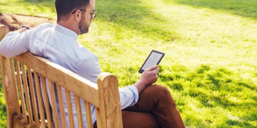 Homem lendo no Kindle em um parque